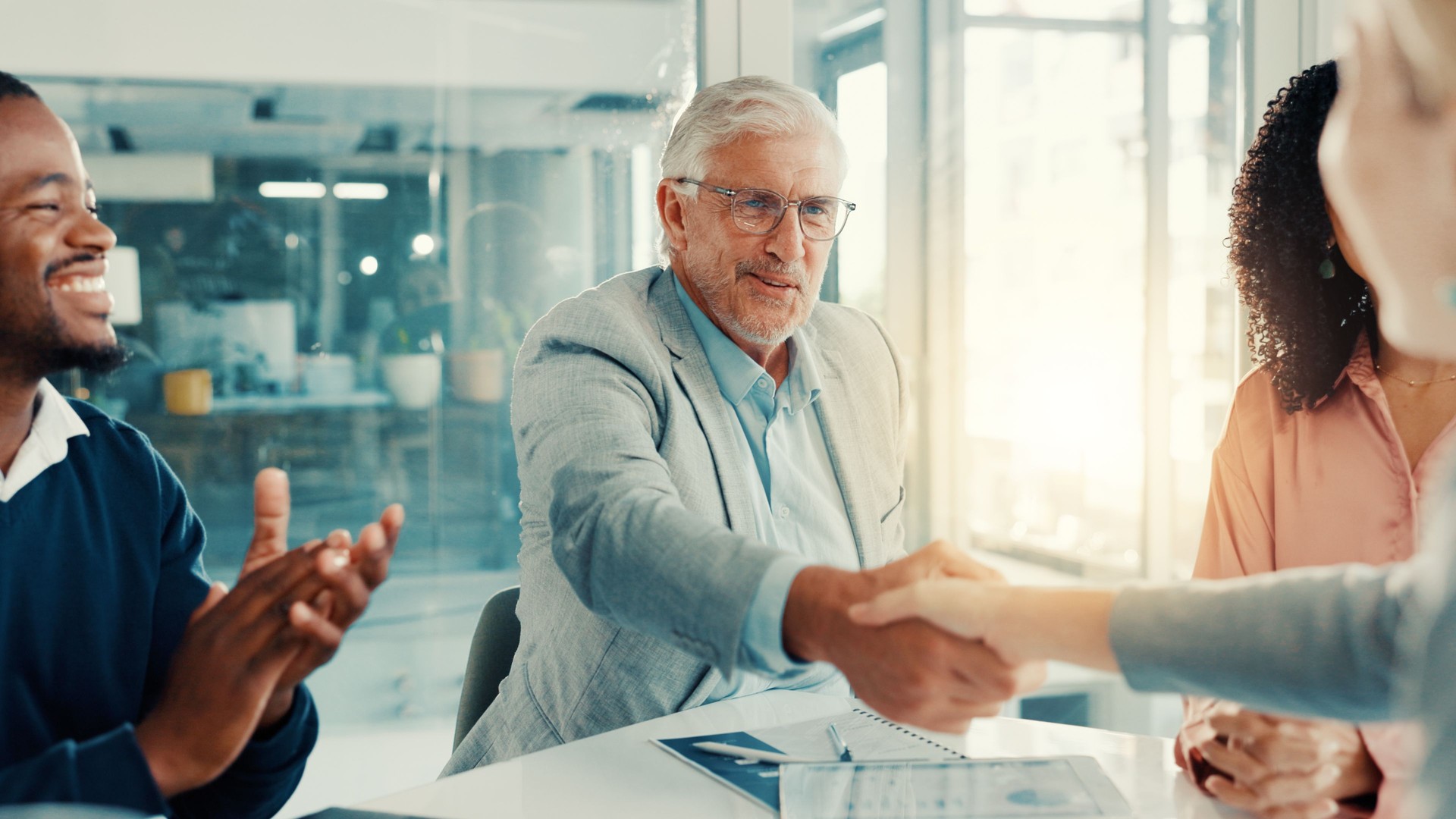 Handshake, applause and business people in office for meeting with finance deal or partnership. Agreement, clapping and financial advisors with shaking hands for congratulations on investment goal.